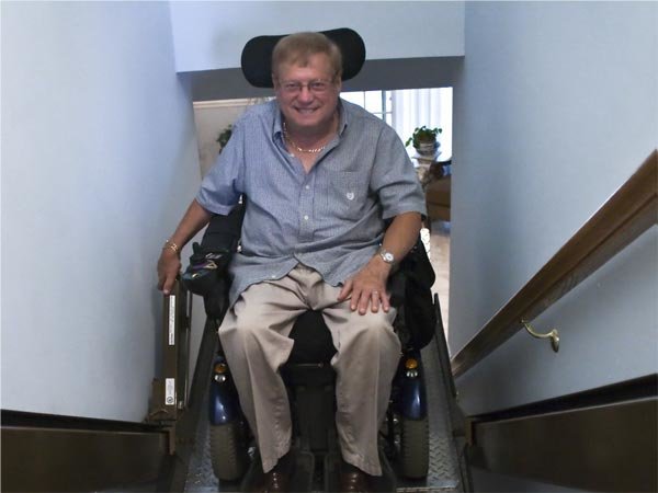 Man riding an incline platform wheelchair lift