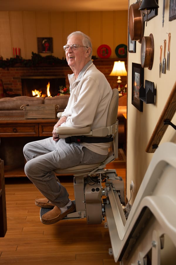 man smiling while sitting on stairlift in his home
